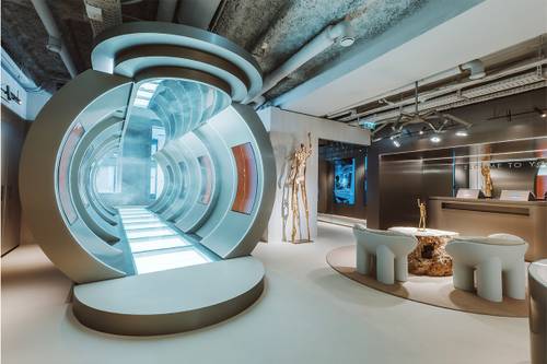 Futuristisches Interieur mit einem leuchtenden Tunnel, modernen Sitzgelegenheiten und einem Empfangsbereich, der sich durch elegantes Design und metallische Akzente auszeichnet.