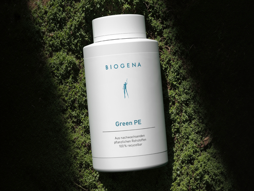 Sticlă albă de supliment BIOGENA Green PE pe fundal de mușchi verde, iluminație naturală, text albastru.