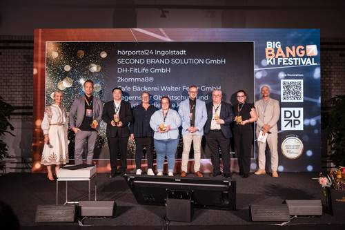 On the stage of the Big Bang AI Festival, a group of people are standing with awards in their hands; in the background, a list of company names can be seen on a screen.