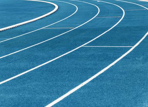 Geschwungene Bahnen einer blauen Laufbahn mit weißen Linien, die ein dynamisches Muster bilden.
