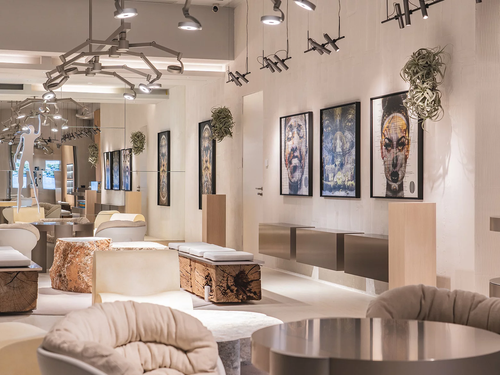 Moderne Kunstgalerie mit zeitgenössischen Sitzgelegenheiten, abstrakten Porträts an den Wänden, warmer Beleuchtung und einer Mischung aus Holz- und Metallelementen in der Dekoration.