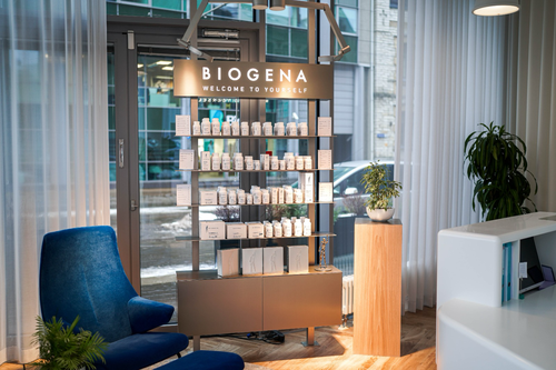 Ausstellung von Biogena-Produkten in Regalen in einem modernen, gut beleuchteten Laden mit einem blauen Stuhl, Pflanzen und großen Fenstern im Hintergrund