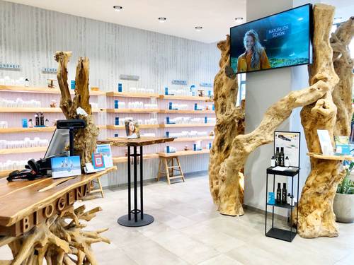 Modernes Ladendesign mit Holzdekor, Regalen mit Produkten, einer Theke mit digitalem Bildschirm und rustikaler Ästhetik
