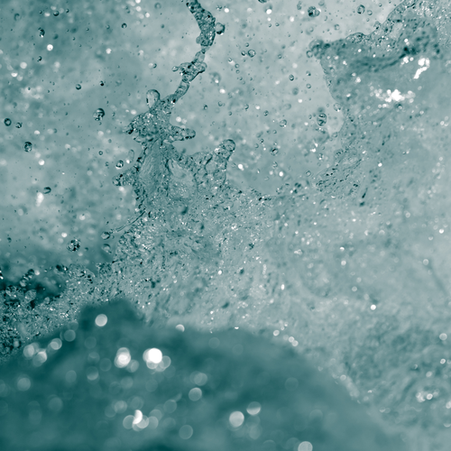 Nahaufnahme von spritzenden Wassertropfen, eingefangen mitten in der Luft vor einem blaugrünen Hintergrund – ein dynamisches und erfrischendes Bild.