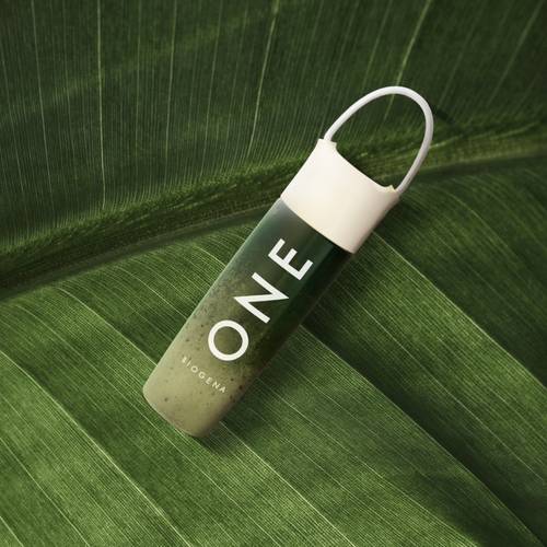 O sticlă verde etichetată „ONE”, cu capac alb, așezată pe un fundal de frunză verde mare.