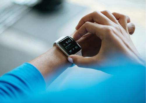 Person, die mit einer Smartwatch interagiert, auf der 5:42 und Fitness-Symbole angezeigt werden. Sie trägt einen blauen Ärmel.