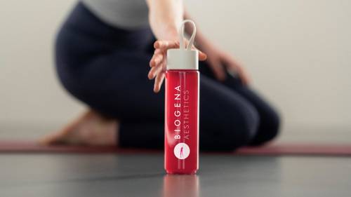 Flasche mit BIOGENA AESTHETICS-Logo, gehalten von einer Person in Yogapose, auf einem Yoga-Matte.