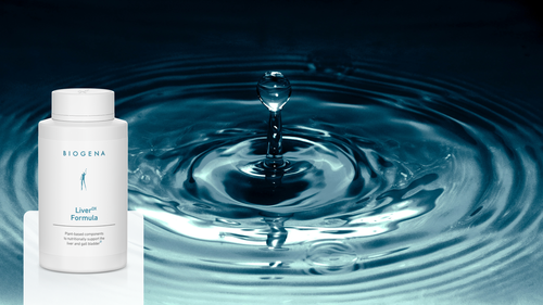 A bottle of Biogena Liver Formula is placed in front of a water droplet causing ripples, symbolizing purity and health benefits.