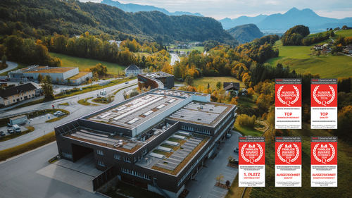 Foto aérea de un edificio industrial moderno con un paisaje montañoso de fondo; a la derecha se ven los logotipos de los premios.