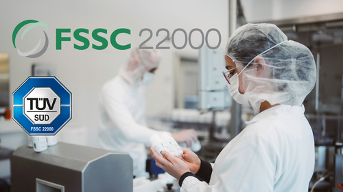 Zwei Laborangestellte in Schutzkleidung prüfen Dosen. Die Logos «FSSC 22000» und «TÜV SÜD» sind zu sehen, was auf eine zertifizierte Umgebung hindeutet.