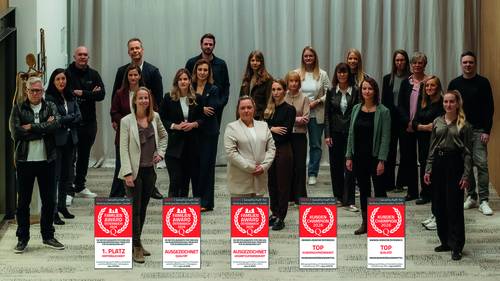 Un grupo de personas que está ahí dentro, detrás de cinco carteles de premios, y que sonríe a la cámara.