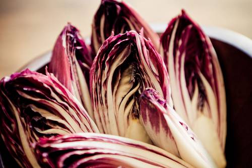 Close-up of fresh radicchio leaves showcasing their vibrant purple and white colors, arranged in a bowl.