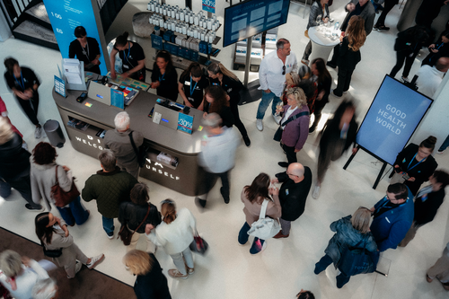 Menschenmenge bei einem BIOGENA Event in Salzburg, die sich im Empfangsbereich mit Displays und Informationsschildern über die „Good Health World" austauscht.