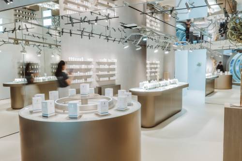Modernes Ladendesign mit eleganten, geschwungenen Holzregalen, in denen Kosmetikprodukte präsentiert werden. Spiegel und sanfte Beleuchtung schaffen ein elegantes Ambiente.
