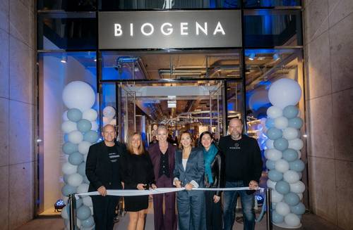 Gruppenfoto vor dem Eingang des neuen BIOGENA Stores bei der Eröffnungsfeier. Sechs Personen stehen vor dem beleuchteten Eingang und halten ein weißes Band für den symbolischen Ribbon-Cut. Links und rechts des Eingangs stehen große Ballonarrangements in Weiß und Hellblau. Der Store ist modern beleuchtet und im Hintergrund sind Gäste und Innenräume sichtbar.