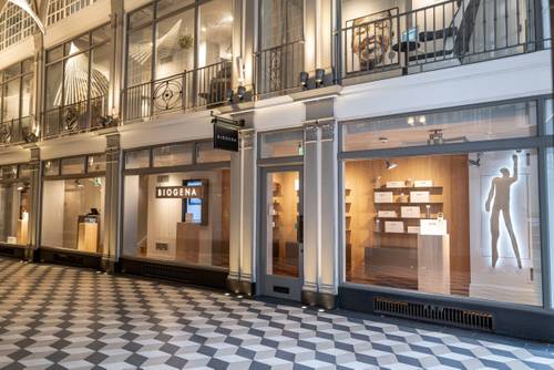 Storefront with large glass windows displaying modern interior and products. The floor features a black and white checkered pattern