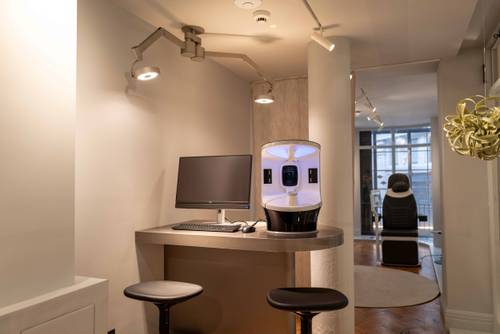Moderne Bürofläche mit einem eleganten Schreibtisch, einem Computer und innovativer Beleuchtung. Im Hintergrund ist ein Stuhl in der Nähe eines großen Fensters zu sehen