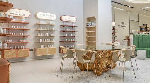 Modernes Ladendesign mit einem Glastisch auf einem Holzgestell, umgeben von Stühlen. Regale präsentieren Hautpflegeprodukte vor weißen Wänden