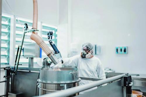 Persoană în echipament de protecție care operează echipamente industriale într-un mediu de producție steril.