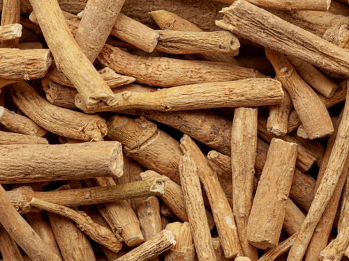 A close-up of dried ashwagandha roots, showing their rough, fibrous texture and light brown colour.