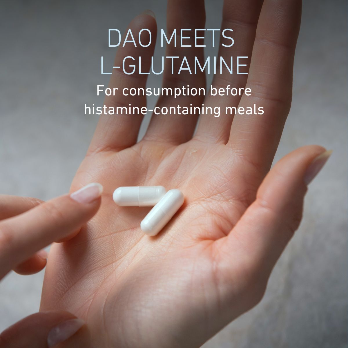 Close-up of hand holding two capsules, text: „DAO meets L-Glutamine to take before histamine-containing meals.