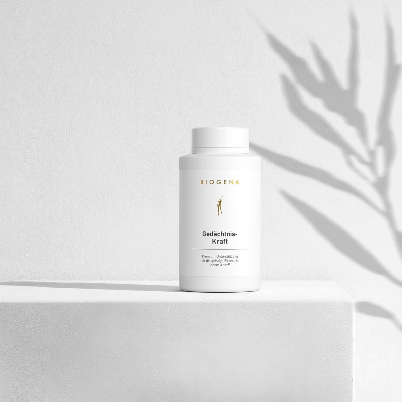 BIOGENA Gedächtnis-Kraft auf einem minimalistischen weißen Regal mit sanften Schatten von einer Pflanze im Hintergrund.