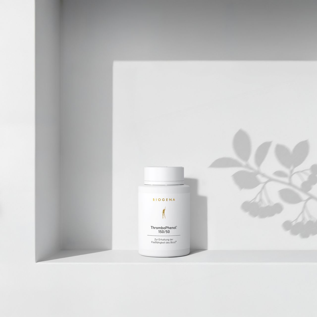 BIOGENA ThromboPhenol 150/50 in a white bottle placed on a shelf, with plant shadows in the background. The label reads "For maintaining blood flow."