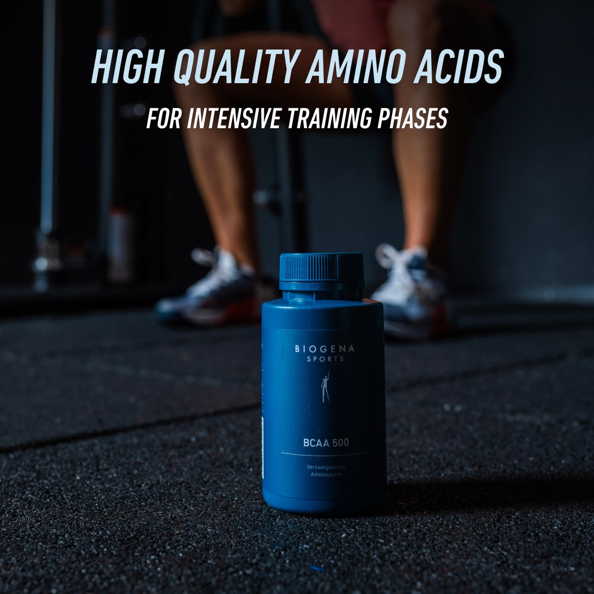 BIOGENA SPORTS BCAA 500 bottle on a gym floor with an athlete in the background. Premium branched-chain amino acids designed to support athletes during intensive training and recovery periods.