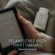 Fľaša BIOGENA MoFerrin 21 položená na látke vedľa osoby držiacej tablet. Železo rastlinného pôvodu v kombinácii s vitamínom C pre uvedomelé stravovanie.