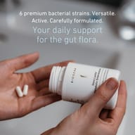 Omni Lactis® Metabolic Enterococcus with six premium bacterial strains. Capsules are dispensed into the hand, representing daily support for the gut microbiome through a carefully formulated probiotic blend.
