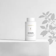 BIOGENA Ashwagandha Triple Superior in una bottiglia bianca, appoggiata su una superficie, con ombre di piante sullo sfondo. L'etichetta riporta "Con Ashwagandha KSM-66® premium e 40 mg di withanolidi."