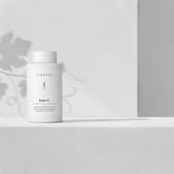 BIOGENA Ester-C® supplement bottle on a minimalist white background with soft plant shadows. Premium vitamin C formula with Ester-C®, quercetin and citrus bioflavonoids.