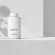 BIOGENA Neurosagena® B-Komplex active on a minimalist white shelf with soft shadows from a flower in the background.
