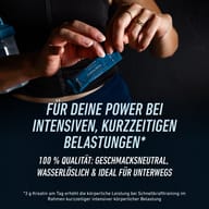 Športovkyňa otvára vrecúško BIOGENA SPORTS Creatine Sticks. Kreatín bez chuti je rozpustný vo vode, praktický na cesty a vhodný ako podpora pri krátkodobej, intenzívnej fyzickej záťaži.