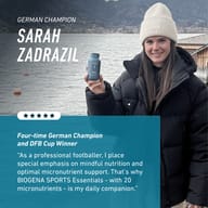 German football champion Sarah Zadrazil holding BIOGENA Sports Essentials outdoors near a lake. She highlights the importance of mindful nutrition and daily micronutrient support with 20 micronutrients as part of her ath
