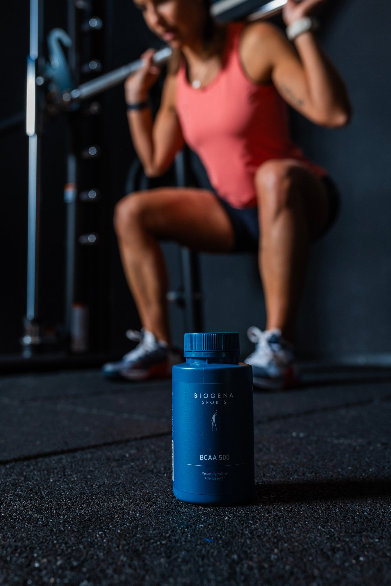 BIOGENA SPORTS BCAA 500 flacon din plastic, deschis, capsule, ganteră, podea pătată