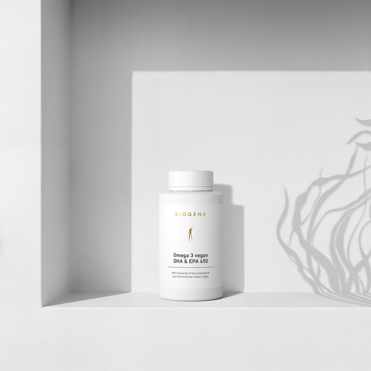 BIOGENA Omega 3 vegan DHA & EPA 450 pe o etajeră albă minimalistă, cu umbre ușoare proiectate de o plantă în fundal.
