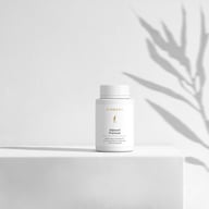 BIOGENA fit@work® Premium Nahrungsergänzungsmittel in weißer Dose auf minimalistischem Hintergrund mit Pflanzenschatten. Premiumformel für Performance und Resilienz mit Ubiquinol, Vitaminen und Mineralstoffen.