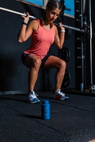 Biogena Sports BCAA 500 flacon, recipient albastru pe podea, persoană cu halteră la sală