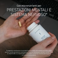 Ręka trzyma otwartą butelkę Biogena Antistress Formula z kapsułką w drugiej ręce, tekst opisujący wsparcie magnezu, kwasu pantotenowego, kwasu foliowego, witaminy B6 i B12 dla nerwów, psychiki, funkcji poznawczych i ukła