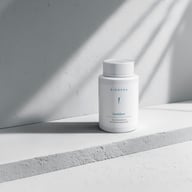 Flacon Biogena ConfiZym, flacon din plastic alb, suprafață albă, perete gri, umbre
