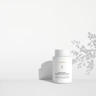 BIOGENA Omni Lactis Metabolic Enterococcus su uno scaffale bianco minimalista con ombre morbide proiettate da una pianta sullo sfondo.
