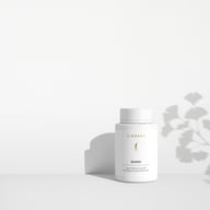 Supliment BIOGENA QinkGo® într-un flacon alb pe fundal minimalist cu lumină și umbră. Formula Heart & Brain cu extract de ginkgo și vitamina B1 pentru susținerea inimii și a creierului.