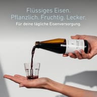 BIOGENA MoFerrin liquid Herbal Elixier wird aus der Flasche in ein Glas gegossen. Flüssiges pflanzliches Eisen in fruchtiger Form für die tägliche Eisenversorgung.