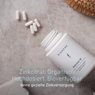Geöffnete BIOGENA Zinkcitrat 30 Dose mit Kapseln und Haarbürste. Hochdosiertes, bioverfügbares Zinkcitrat für eine gezielte Zinkversorgung.