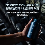 Ruka drží balenie BIOGENA SPORTS ZMB6 pred stojanom s činkami. Produkt je prezentovaný ako partner pre intenzívne tréningové a súťažné fázy s obsahom zinku, horčíka a vitamínu B6.