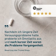 Eine Kapsel liegt neben einem Glas auf einer Steinoberfläche. Daneben ist eine 5-Sterne-Bewertung von Trusted Shops mit einem Kundenzitat zu BIOGENA Omni Lactis® 20 über verbesserte Verdauung nach kurzer Anwendungszeit.
